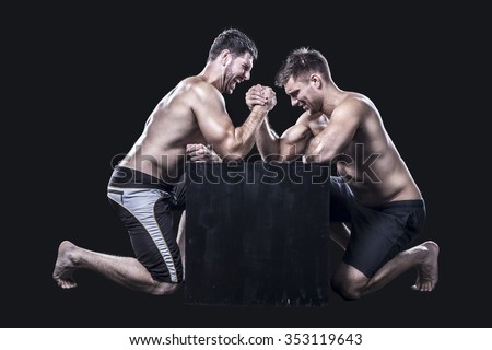 Two armwrestlers, have an arm wrestling match on a black box shirtless