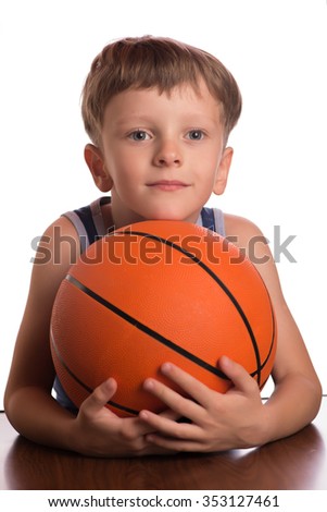 The boy smiled embracing a basketball ball to a breast two hands