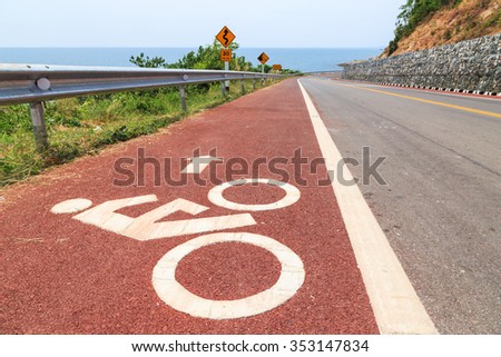 Symbol of bicycle at bike lane on steep downhill descent with scenery along the beach road