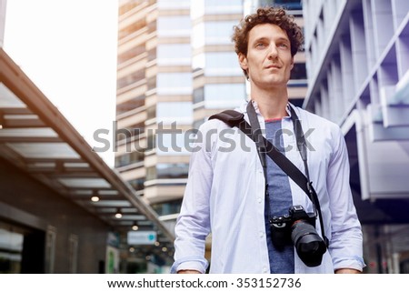 Happy male tourist in casual clothes in city with camera