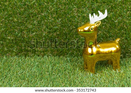 Beautiful golden reindeer toy , on green grass background