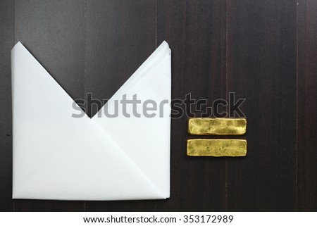 The white color paper napkin on the dark color wooden dining table floor and gold bar represent the cleaning material and business abstract concept related idea.