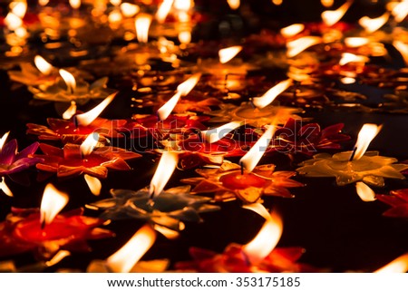 Close focus onto bright candle floating on pool of hot oil in public temple