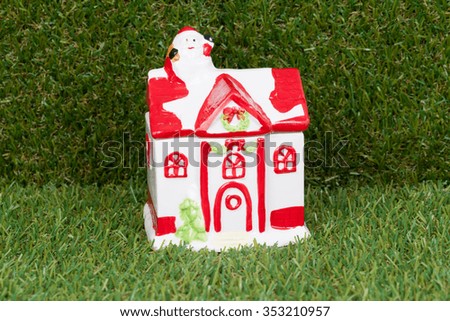 Little christmas house on green glass bacground with Santa Claus climbing a house