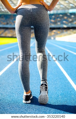 Close up photo of young sportswoman ready to run on racetrack outdoors. Fit woman is at large nice modern stadium