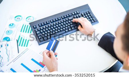 Close up photo of young businessman. Young businessman working with computer and holding credit card. Focus on keyboard