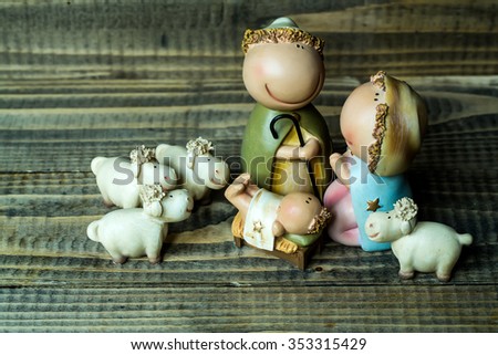 Closeup view of decorative celbrating Christmas and Jesus birth figurines of holy vergin Mary Josepd newborn child with few white sheeps standing on wooden background, horizontal picture