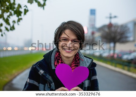 Smiling woman holding paper heart