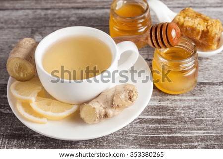 A white cup of green natural tea with ginger, lemon and honey on wooden rustic background. Healthy drink. Hot winter beverage concept.