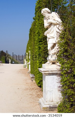 Color DSLR picture of ancient sculptures along a row of hedges on the grounds of the Palace at Versailles, France.  Famous tourist attraction and destination. Vertical with copy space for text.