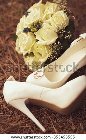Picture of female white wedding shoes with a bouquet 