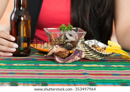 Young brunette girl enjoying a delicious seafood cebiche, typical ecuadorian plate along with a beer