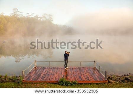 Photographer take a picture of beautiful sunrise and fog in lake
