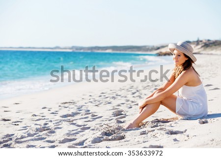 Portrait of young pretty woman with hat sitting on the beach
