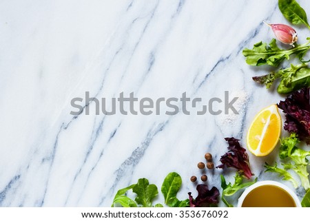 Healthy green lettuce with olive oil, lemon and garlic on marble texture. Background layout with free text space. Bio food, health concept. Top view.