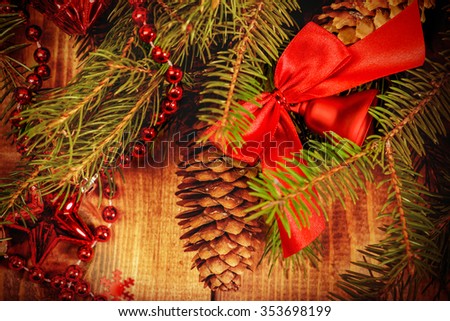 Christmas Border - fir branches with red baubles, bells and snowflakes on a wooden background.