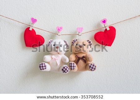 Teddy bear with red heart decoration hanging over wall grunge background
