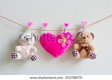 Teddy bear with pink heart decoration hanging over wall grunge background