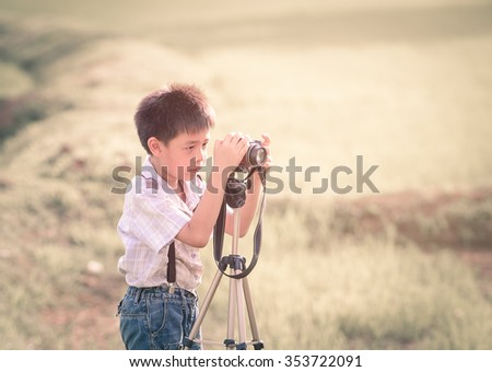 asian boy with classic camera is shooting in the farm