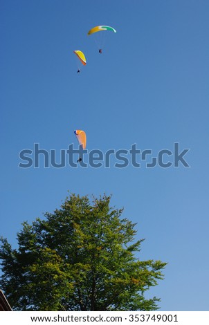 people while practicing paragliding in a blue sky Italy