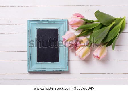 Fresh  spring pink tulips flowers, empty blackboard   on white  painted wooden planks. Selective focus. Place for text.