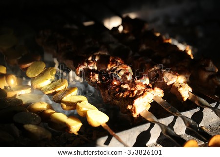 Photo closeup of delicious hot potatoes and meat skewers cooked on grill charbroiled barbecue on brazier on blurred smoky background, horizontal picture 