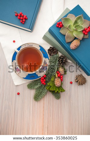 A cup of tea/A cup of black tea, books and coniferous winter composition with pine cones and rowan. Light background