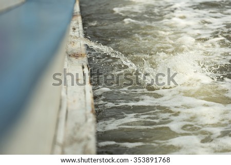Shallow DOF of bilge being pumpt out of boat splashing into sea while boat is moving Royalty-Free Stock Photo #353891768