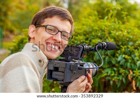 Happy young operator with a video camera shoots video in the park 