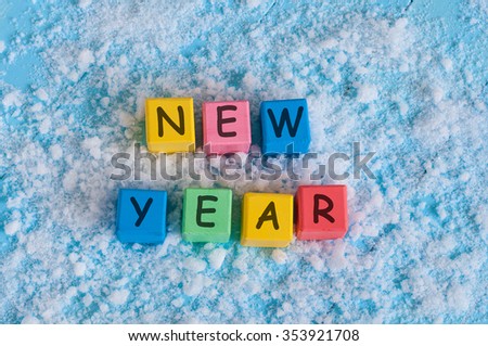happy new year written with toy color cubes. on snow background.