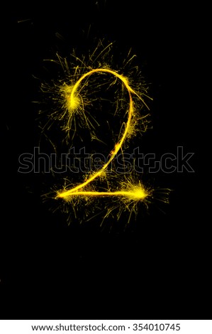 "2" number drawn with bengali sparkles isolated on black background,number from sparkler on black background