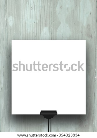 Close-up of one hanged square frame with black clip on blue wooden boards background