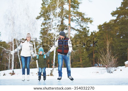 Happy family skating on the rink in winter park