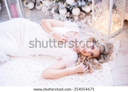 A beautiful young girl lying in white beautiful dress under the Christmas tree