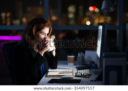 Business woman drinking coffee to get some energy for working overtime Royalty-Free Stock Photo #354097517