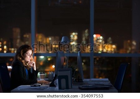 Pretty business woman working alone in dark office Royalty-Free Stock Photo #354097553