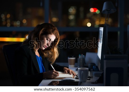 Serious female business executive writing in notepad Royalty-Free Stock Photo #354097562