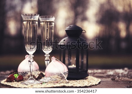 Holidays concept - Two glasses of Champagne and New Year and Christmas decorations outdoors. Selective focus.