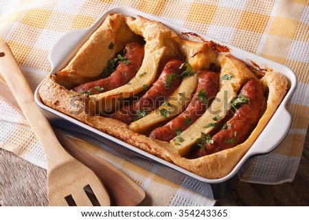 English food: toad in the hole into a baking dish close up on the table. Horizontal
