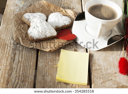 Heart shaped cookies (powdered sugar), cup of coffee, decoration red heart on old wooden table. sunny morning. Christmas breakfast or Valentine's Day Breakfast. Toned image