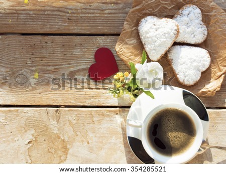 Heart shaped cookies (powdered sugar), cup of coffee, decoration red heart on old wooden table. sunny morning. Christmas breakfast or Valentine's Day Breakfast. Toned image