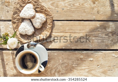 Heart shaped cookies (powdered sugar), cup of coffee, decoration on old wooden table. sunny morning. Christmas breakfast or Valentine's Day Breakfast. Toned image