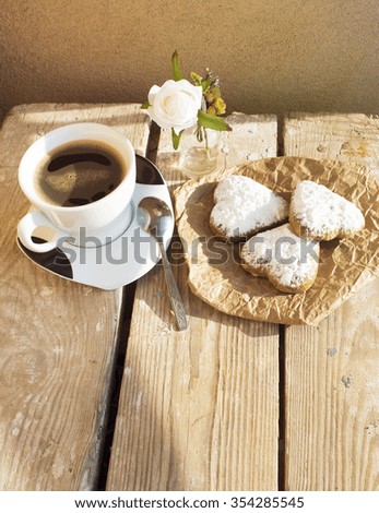 Heart shaped cookies (powdered sugar), cup of coffee, decoration on old wooden table. sunny morning. Christmas breakfast or Valentine's Day Breakfast. Toned image