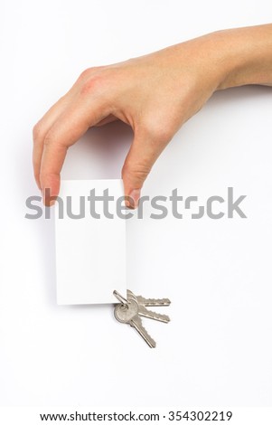 Hand holding a white business visit card, gift, ticket, pass, present close up on white background. Copy space. Real Estate Concept. Top view.