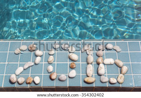 The inscription " 2016 " is laid out by pebble on a pool side