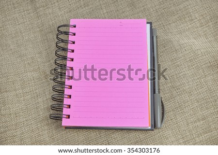 Pink note pad and pen in jut background