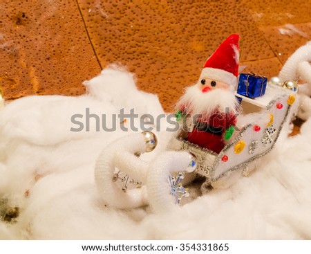 doll of Santa Claus sitting on car  in snow