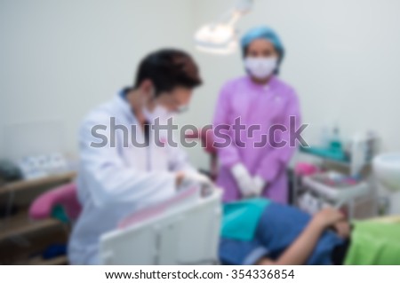 Blurred abstract background of dentistry care unit room interior in dental hospital/ clinic with dentist and assistants working on patient's tooth care using equipment, instrument on dental chair