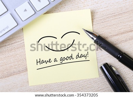 Top view of Have a good day sticky note pasted on the wooden desk with keyboard and pen aside.