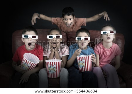 Group of children with 3d glasses and popcorn in a sofa having fun
